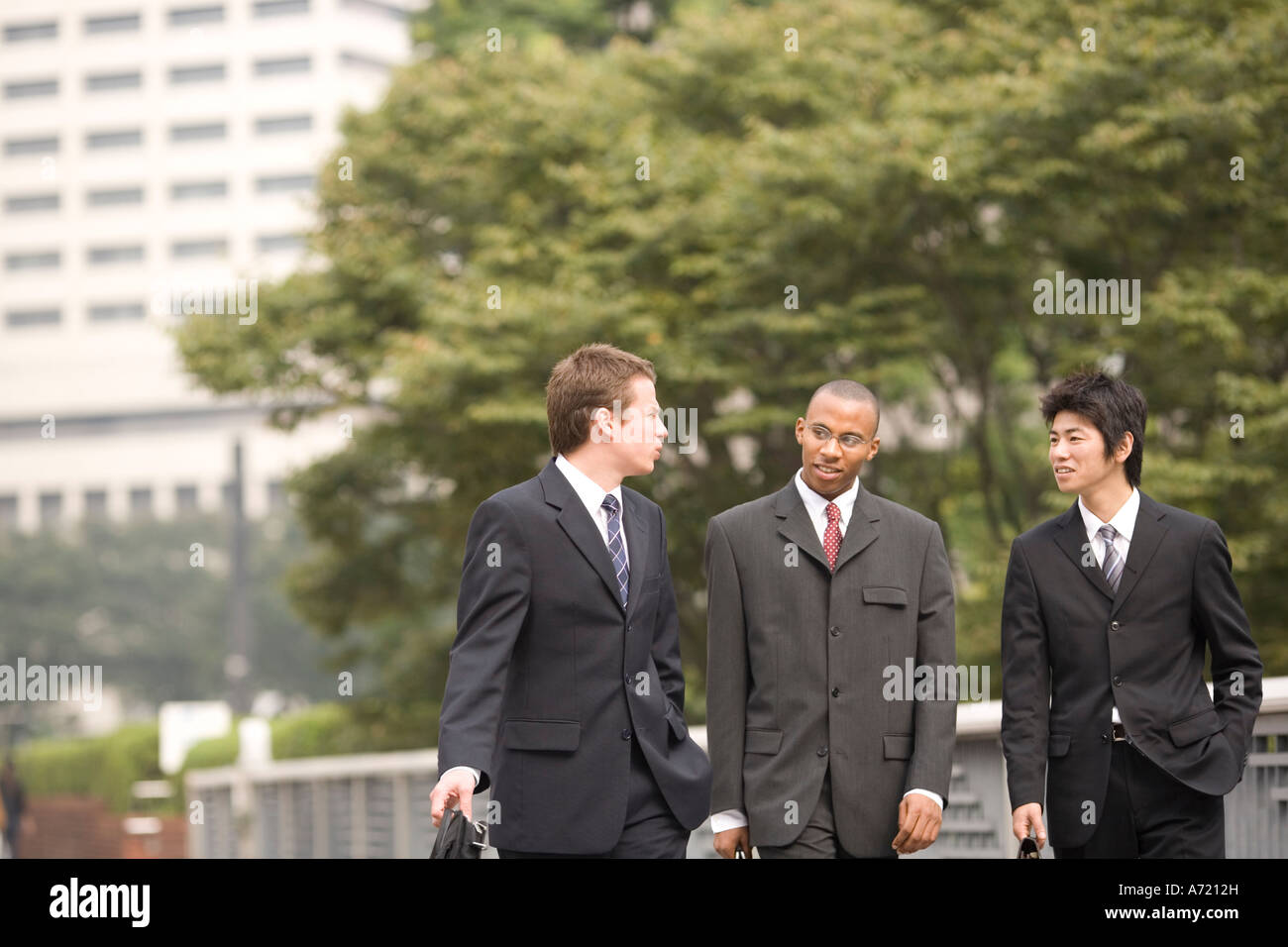 Tre uomini di affari di parlare mentre si cammina Foto Stock