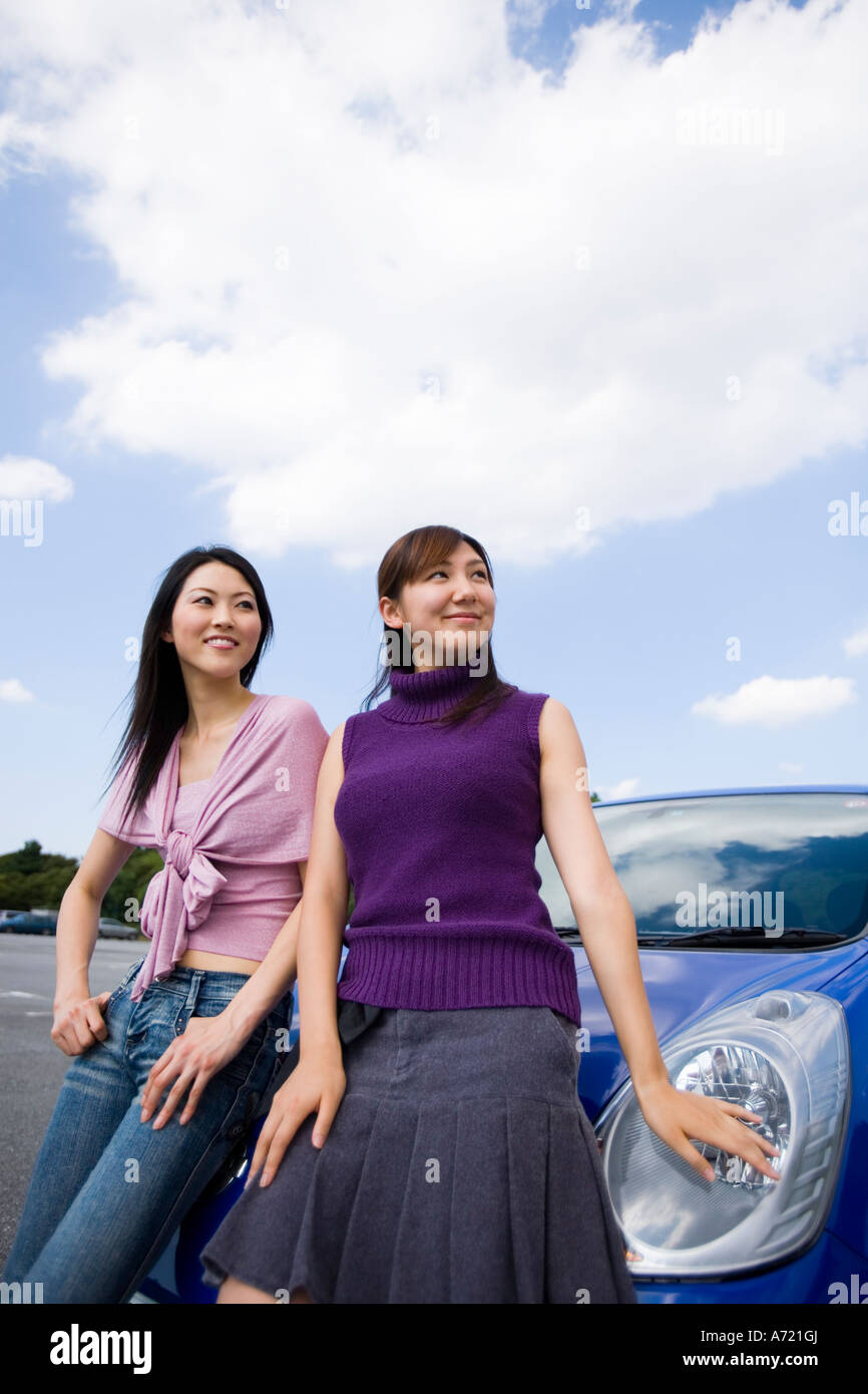 Due giovani donne appoggiata contro l'auto Foto Stock