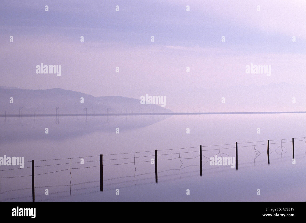 Un grafico foto di un parzialmente sommerso fenceline in un lago Foto Stock