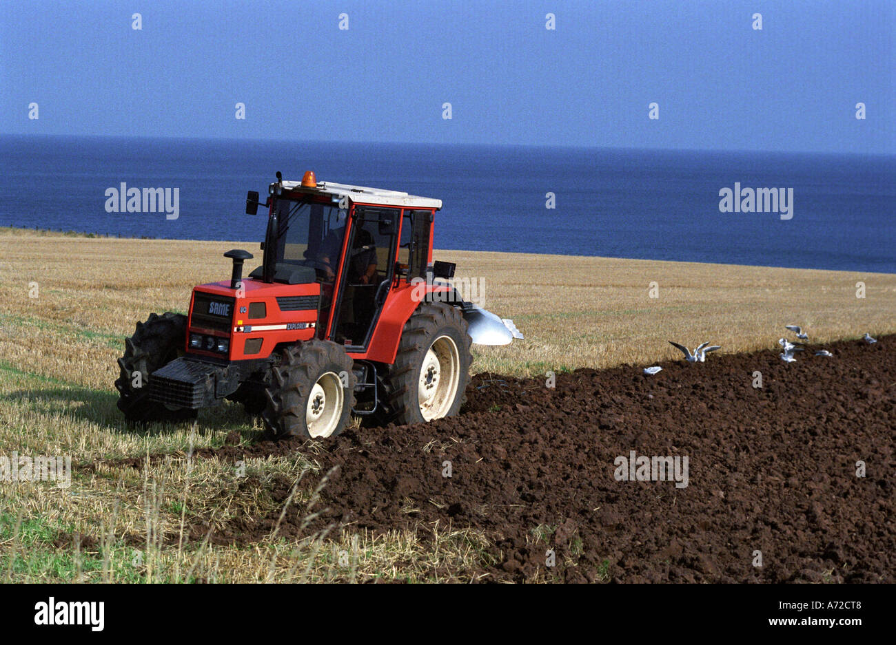 Stesso EXPLORER 60VDT Red Tractor Spring aratura su fattoria costiera con mare visibile all'orizzonte; Nord Berwick nord-est Inghilterra Regno Unito Foto Stock