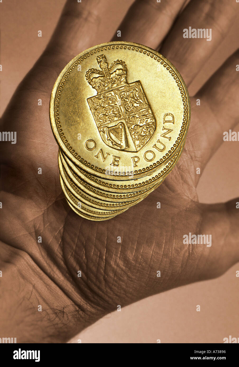 Mano che tiene una pila di UK Pound monete Foto Stock