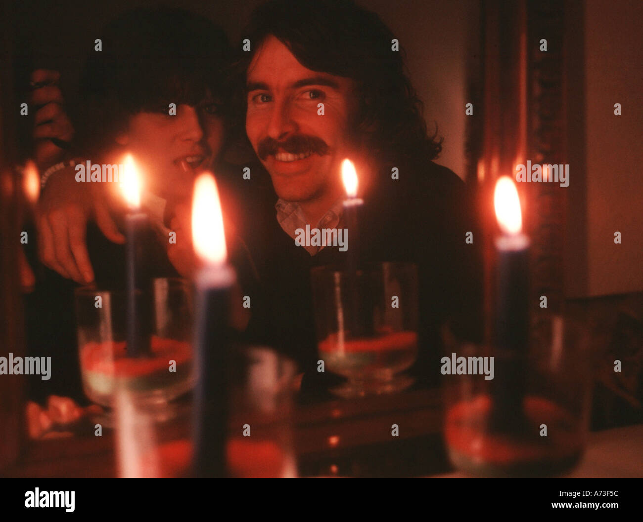 Giovane illuminato da candele negli anni settanta Foto Stock