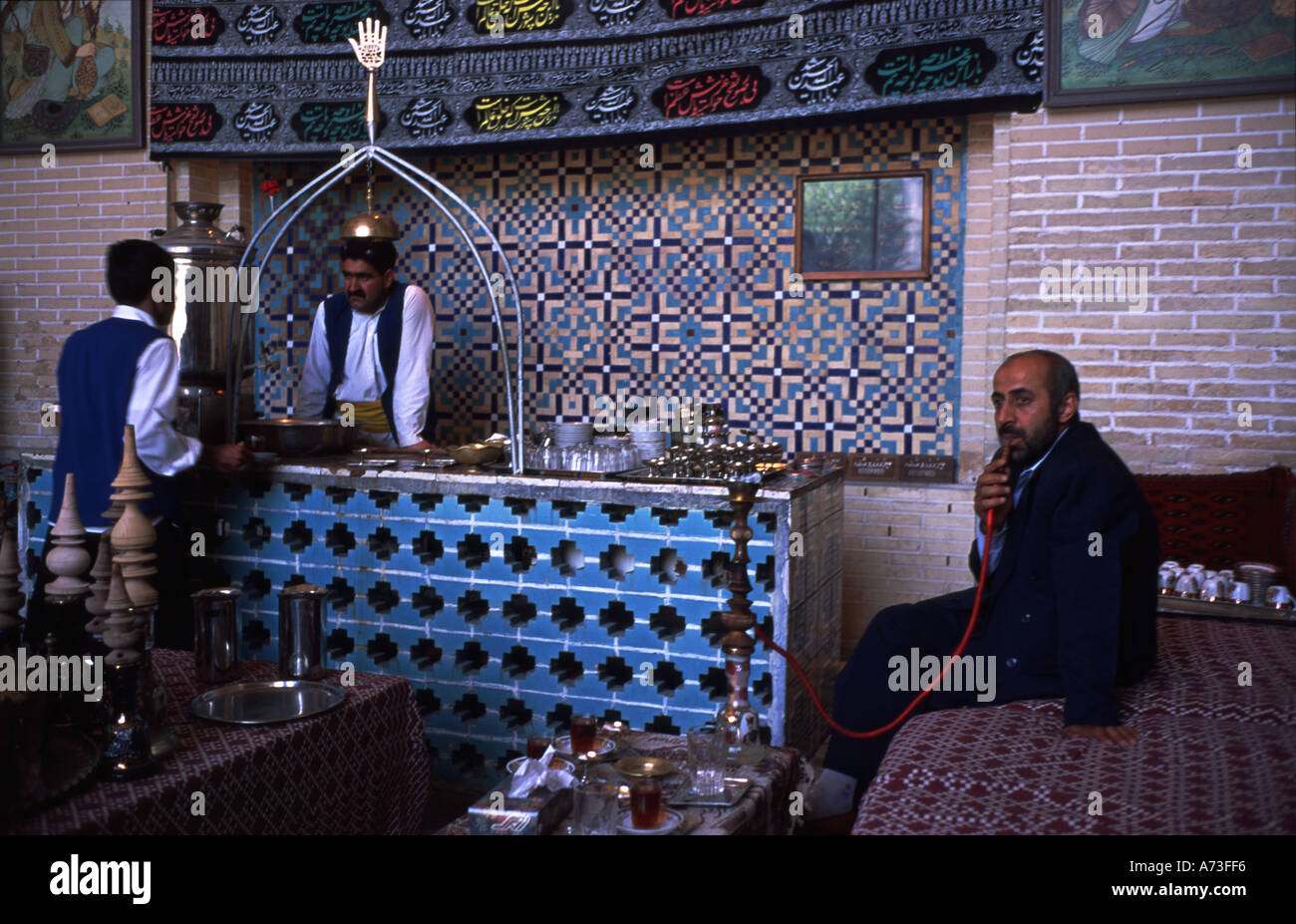 Sala da tè Isfahan Iran casa da tè Esfahan persona fuma acqua pipe saramena Ashura Festival preghiere musulmane su tela a pareti Hassan e Hussein Foto Stock