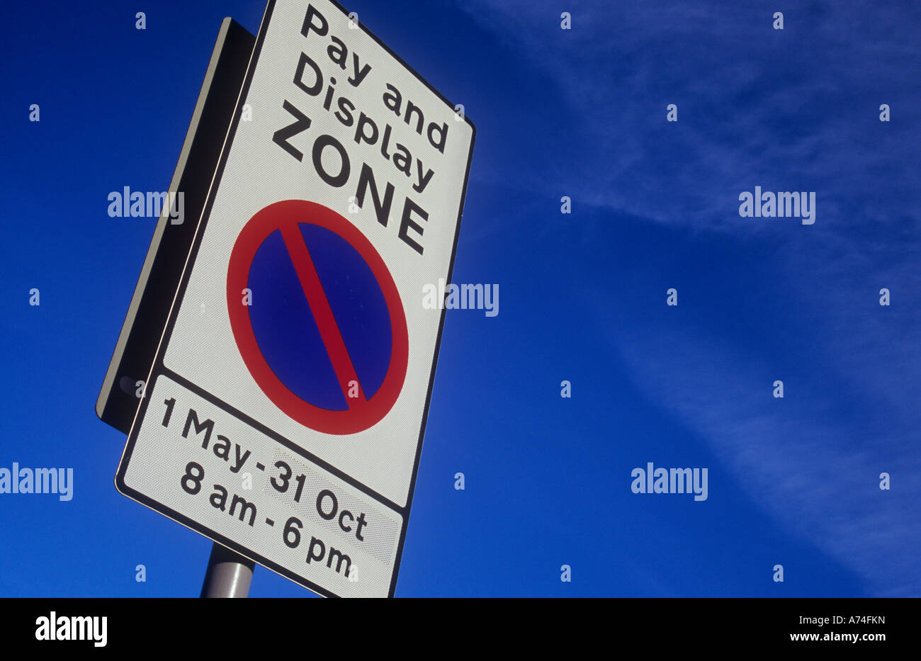 Segno bianco contro il cielo blu con il blu e il rosso a parcheggio limitato e simbolo di pagare e la zona di visualizzazione 1 Maggio al 31 Ott 8am alle 6pm Foto Stock