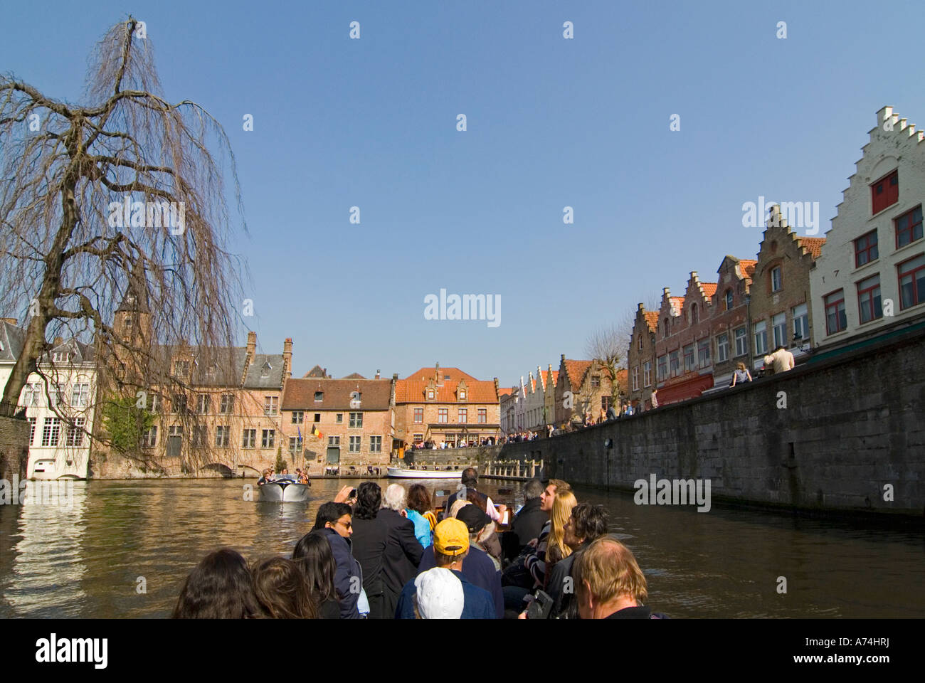 Vista orizzontale di turisti che si godono guidato un viaggio in barca lungo i canali di Bruges in una luminosa giornata di sole. Foto Stock