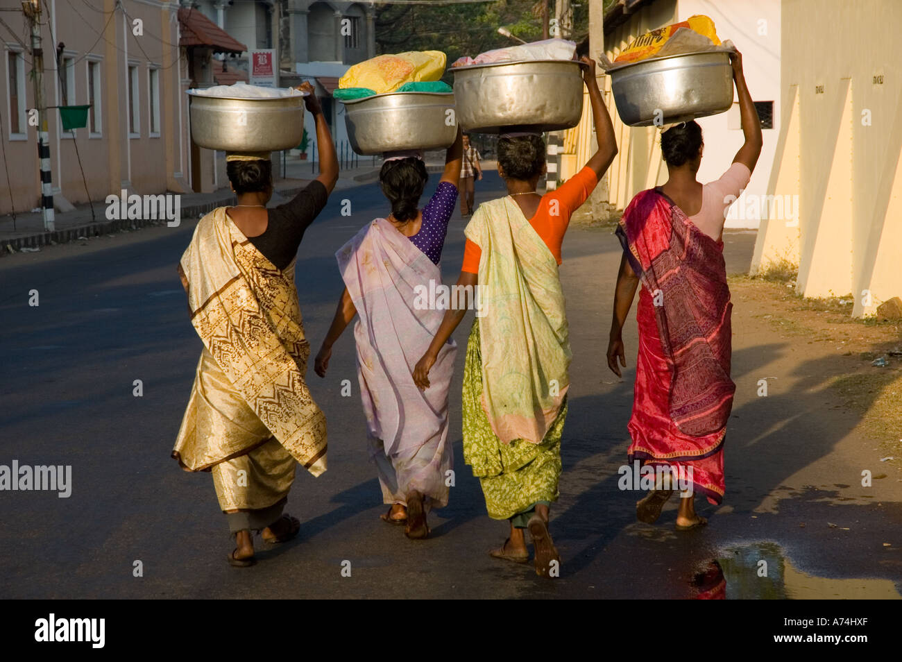 Le donne a piedi lungo una strada con bocce bilanciato sulle loro teste in Kerala Cochin India del Sud Foto Stock