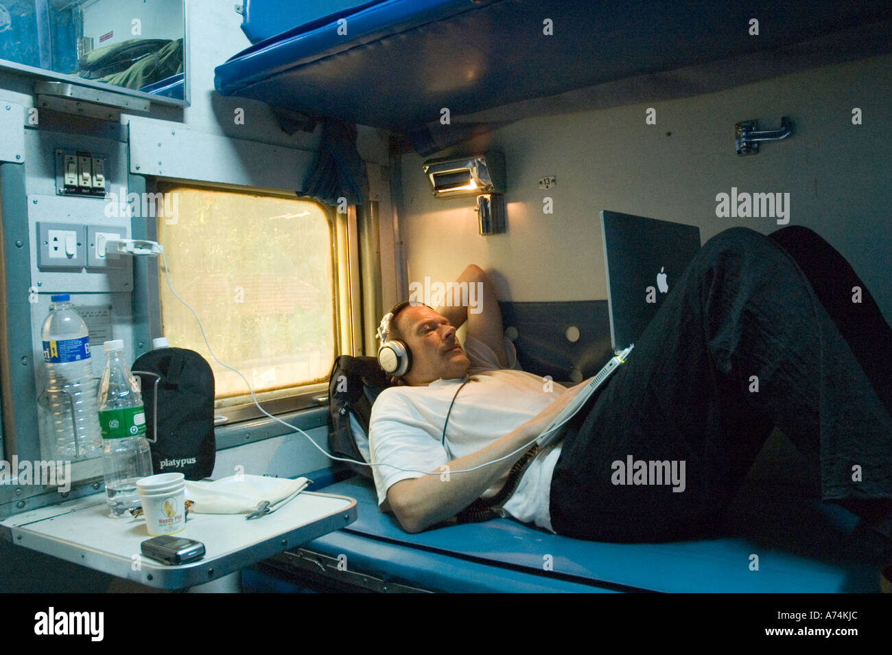 Un uomo che utilizza un computer portatile su un'aria condizionata treno indiano Foto Stock