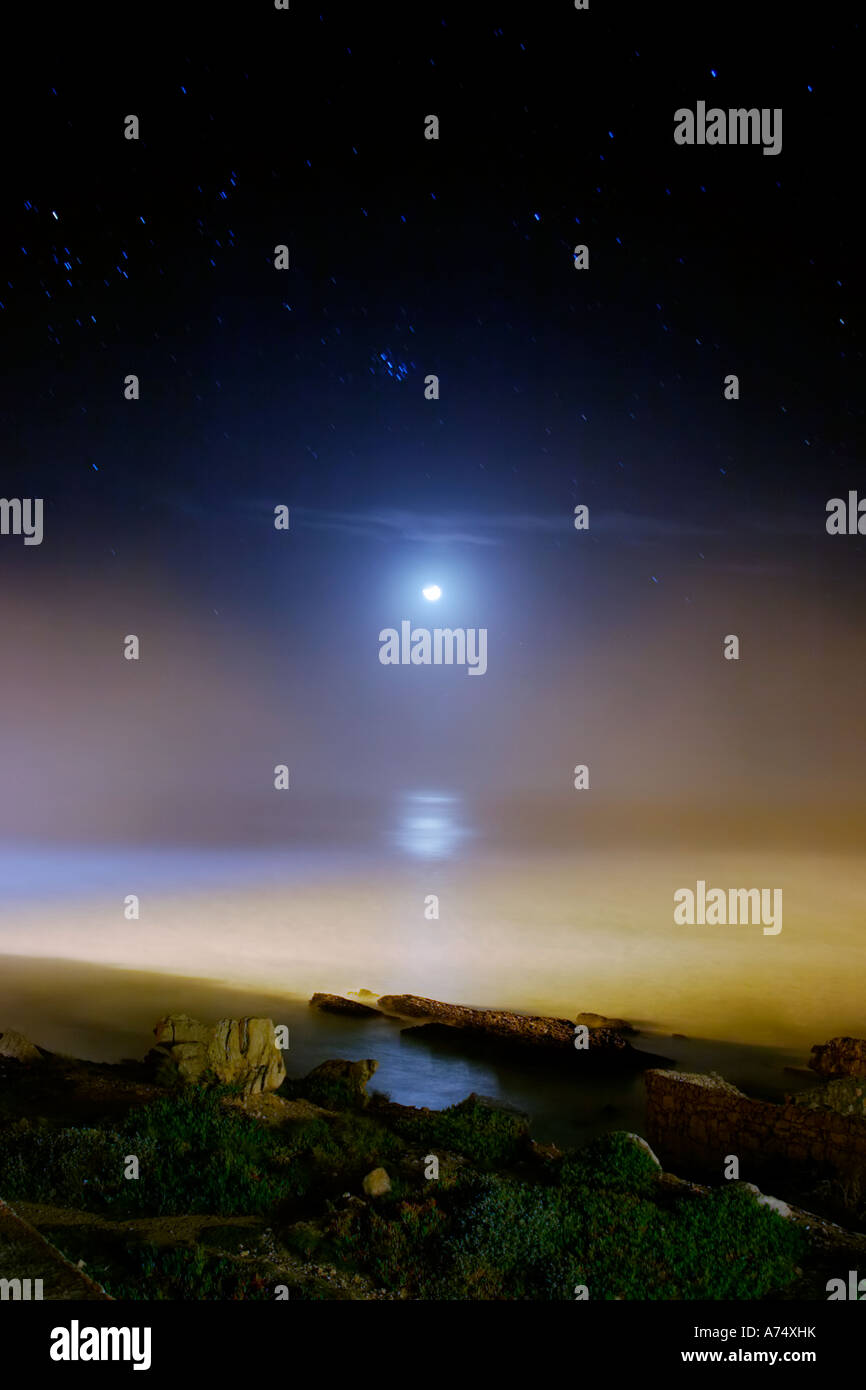 Calare della luna sul mare con le Pleiadi (M45) cluster. Foto Stock