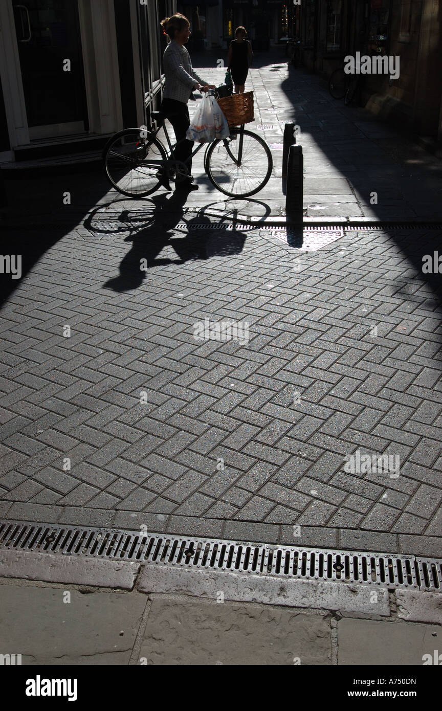 Una forte immagine illuminata da dietro di una donna in sella ad una vecchia bicicletta con Cestino bici Foto Stock