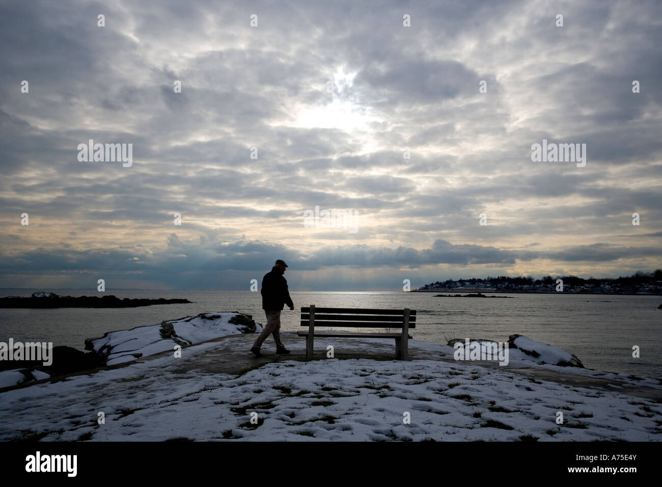 L'uomo cammina lungo il litorale del Connecticut con drammatica cielo e neve invernale Foto Stock