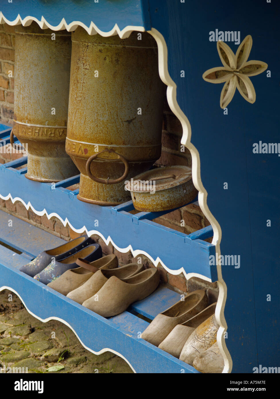 Blu e bianco rack in legno al di fuori di una storica casa colonica con gli zoccoli e due lattine di latte i bidoni Foto Stock