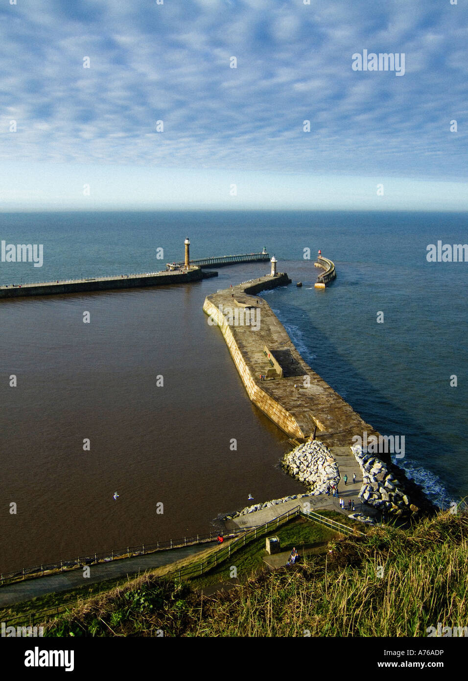 Vista elevata dalla scogliera est di Whitby dei moli est e ovest e dei loro fari con il Mare del Nord che scompare all'orizzonte. Foto Stock