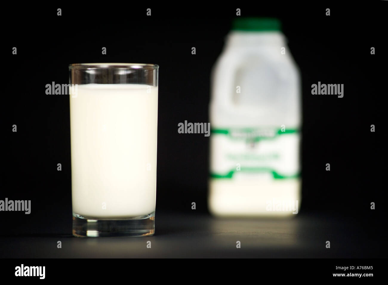 Un bicchiere di latte e di cartone su un puro sfondo nero. Foto Stock