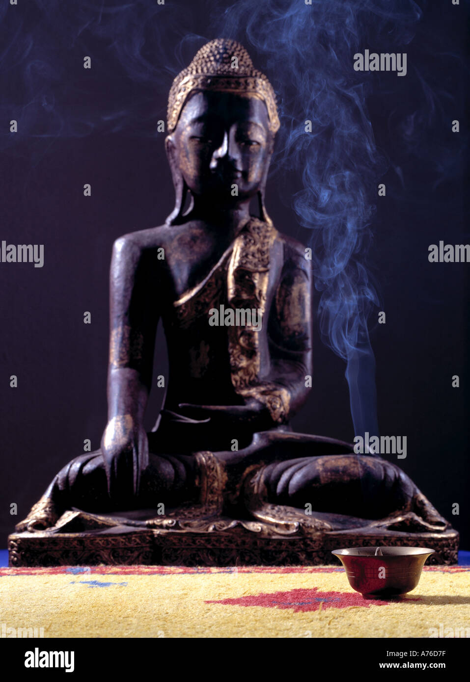 Scultura in legno di Buddha nella parte anteriore del fumo di incenso Foto Stock