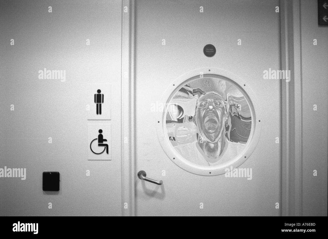 L'uomo urlando come se intrappolata dietro oblò di una porta Foto Stock