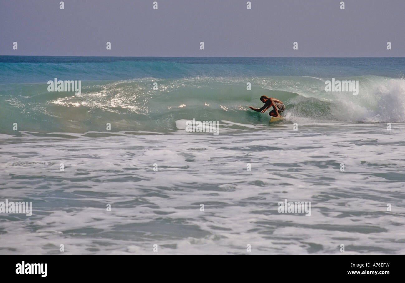 Un surfista giostre in il ricciolo di un'onda Foto Stock