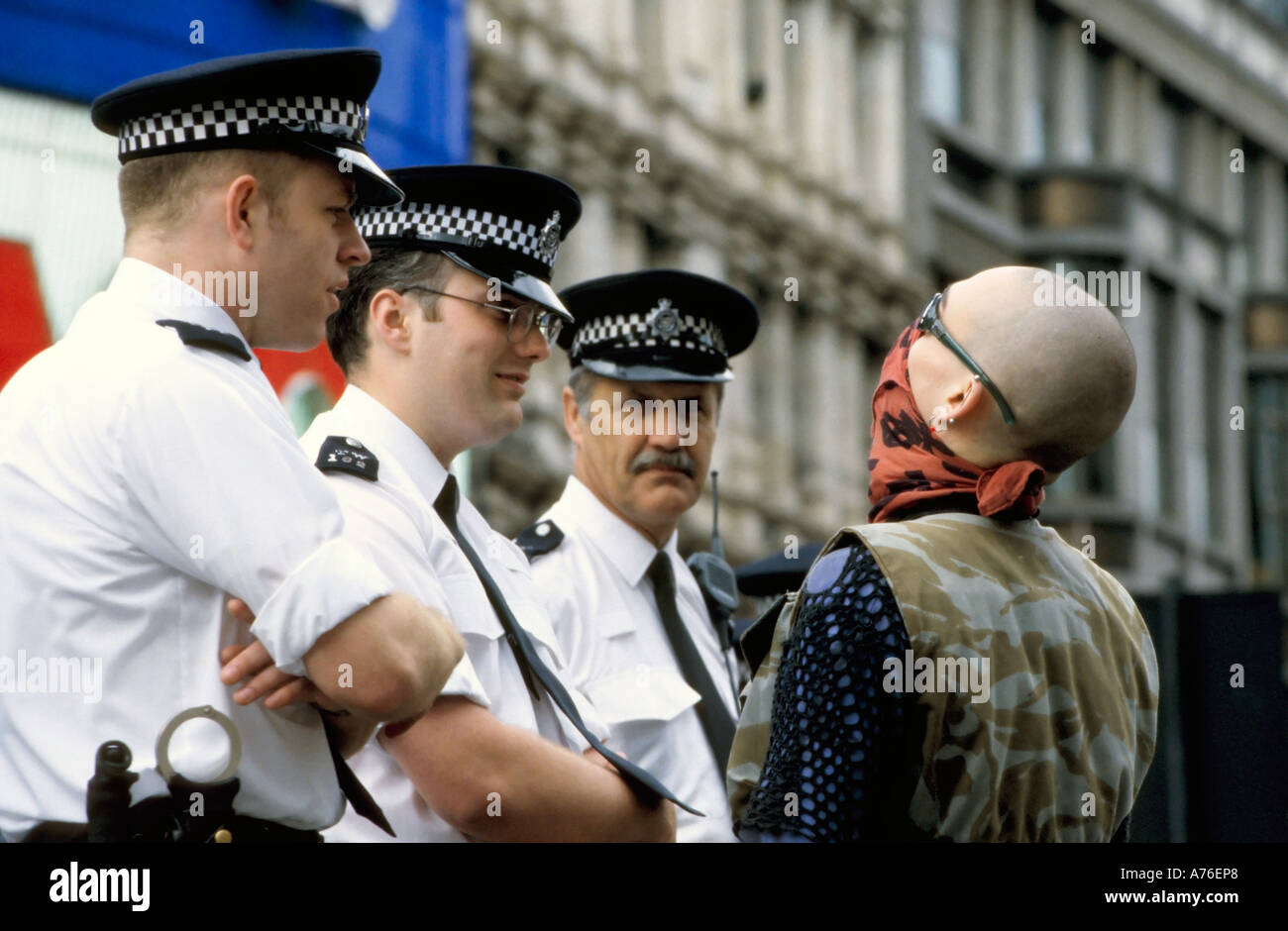 Tre poliziotti parlando a un skinhead dimostrante durante il giorno di maggio dimostrazioni. Foto Stock