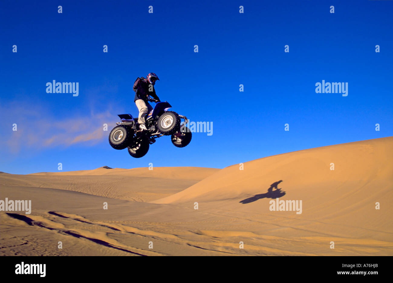Un Quad biker di eseguire salti di freestyle sulle dune di sabbia del deserto namibiano. Foto Stock
