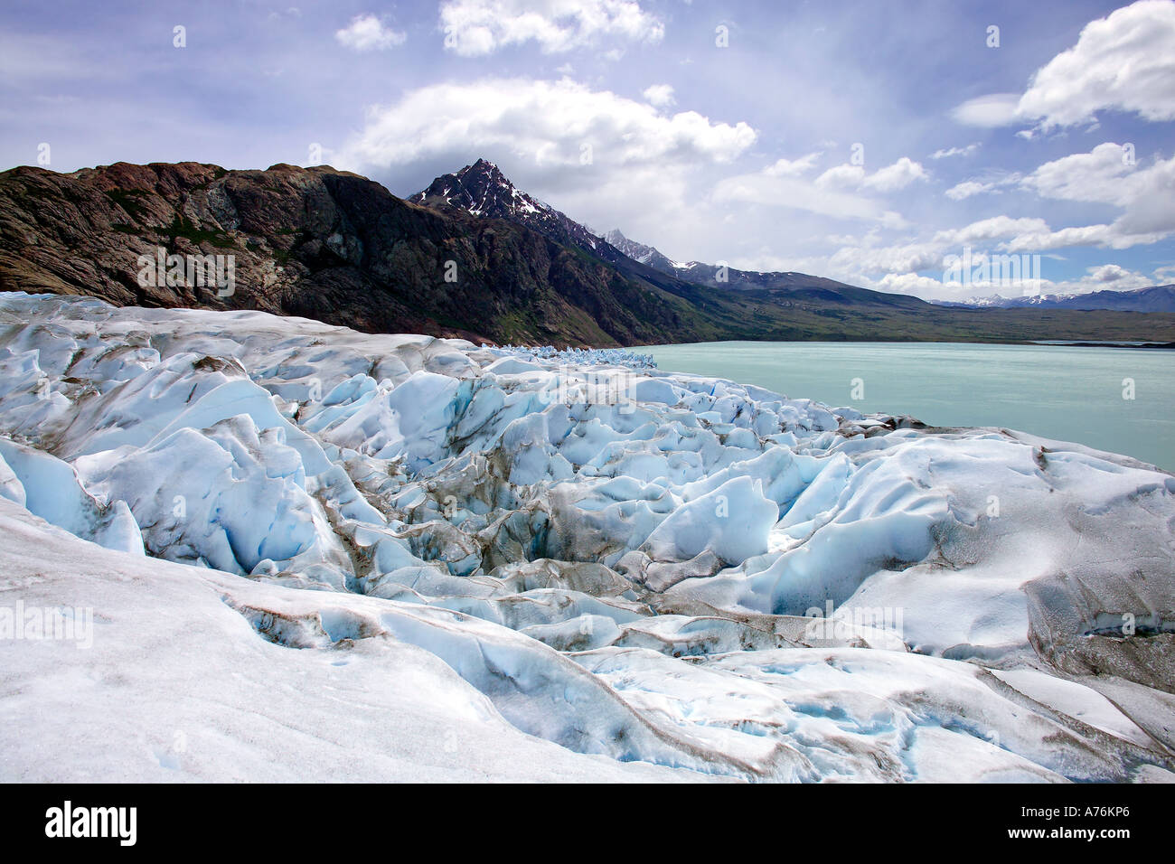Ampio angolo di visione dell'aspro paesaggio ghiacciato e il lago glaciale dalla cima del ghiacciaio Viedma contro un cielo blu. Foto Stock