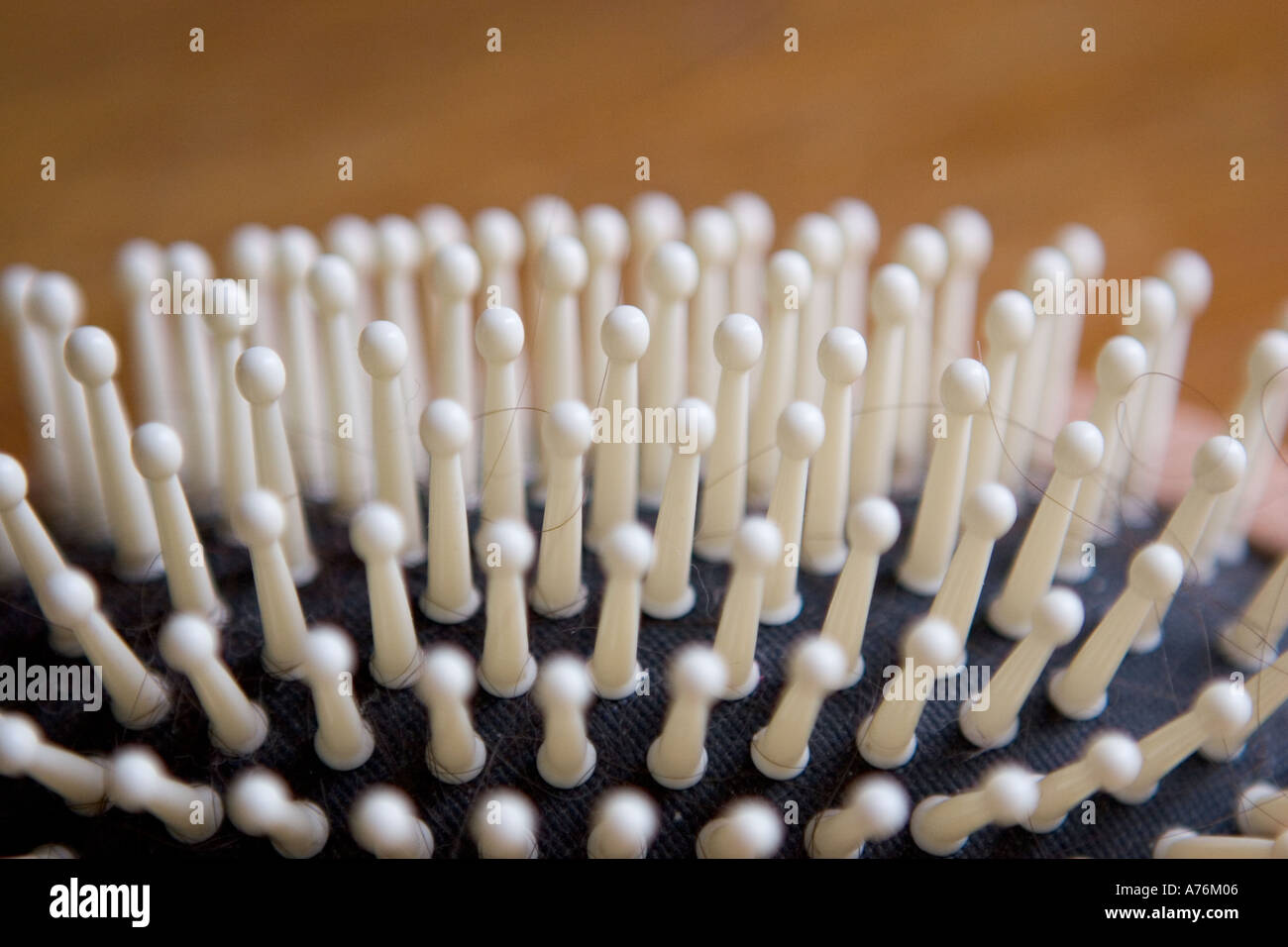 Una chiusura di una spazzola per capelli su una superficie in legno con ciocche di capelli neri intrecciati in setole Foto Stock