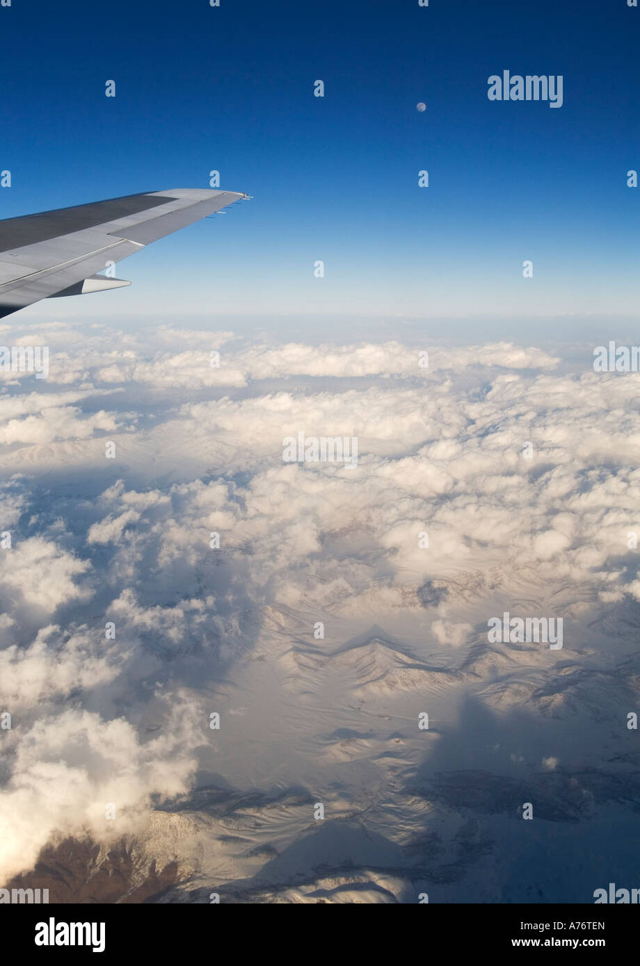 Vista aerea di montagne coperte di neve al tramonto sorvolano la Turchia in inverno con aeromobili ala punta contro il cielo blu e la luna piena Foto Stock