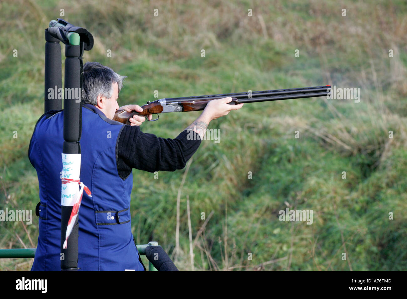 Uomo in tuta blu con tatoo fucile sparo nel campo di ripresa per stare su dicembre giornata di riprese nella contea di Antrim Foto Stock