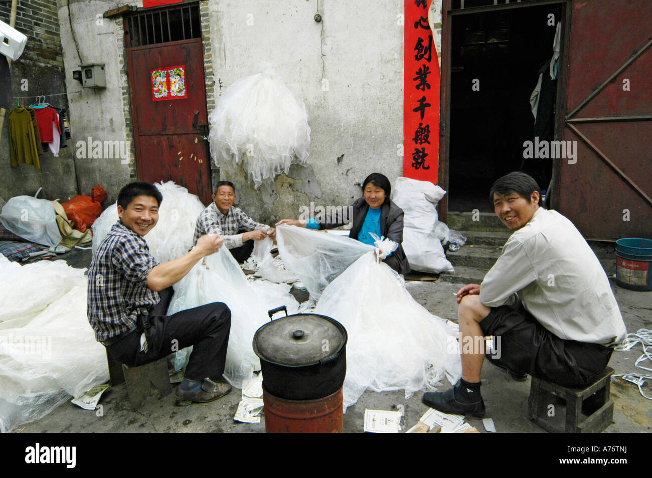 Gli uomini e le donne di smistamento di immondizia di plastica per il riciclaggio, baraccopoli, Cina Foto Stock