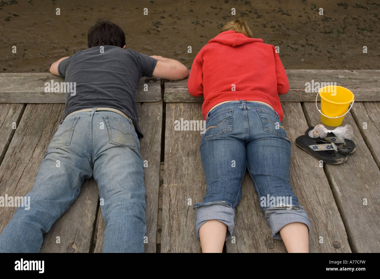 Due giovani che giacciono sul loro stomachi sul pontile in legno la pesca dei granchi Aberdyfi Gwynedd north Wales UK Foto Stock