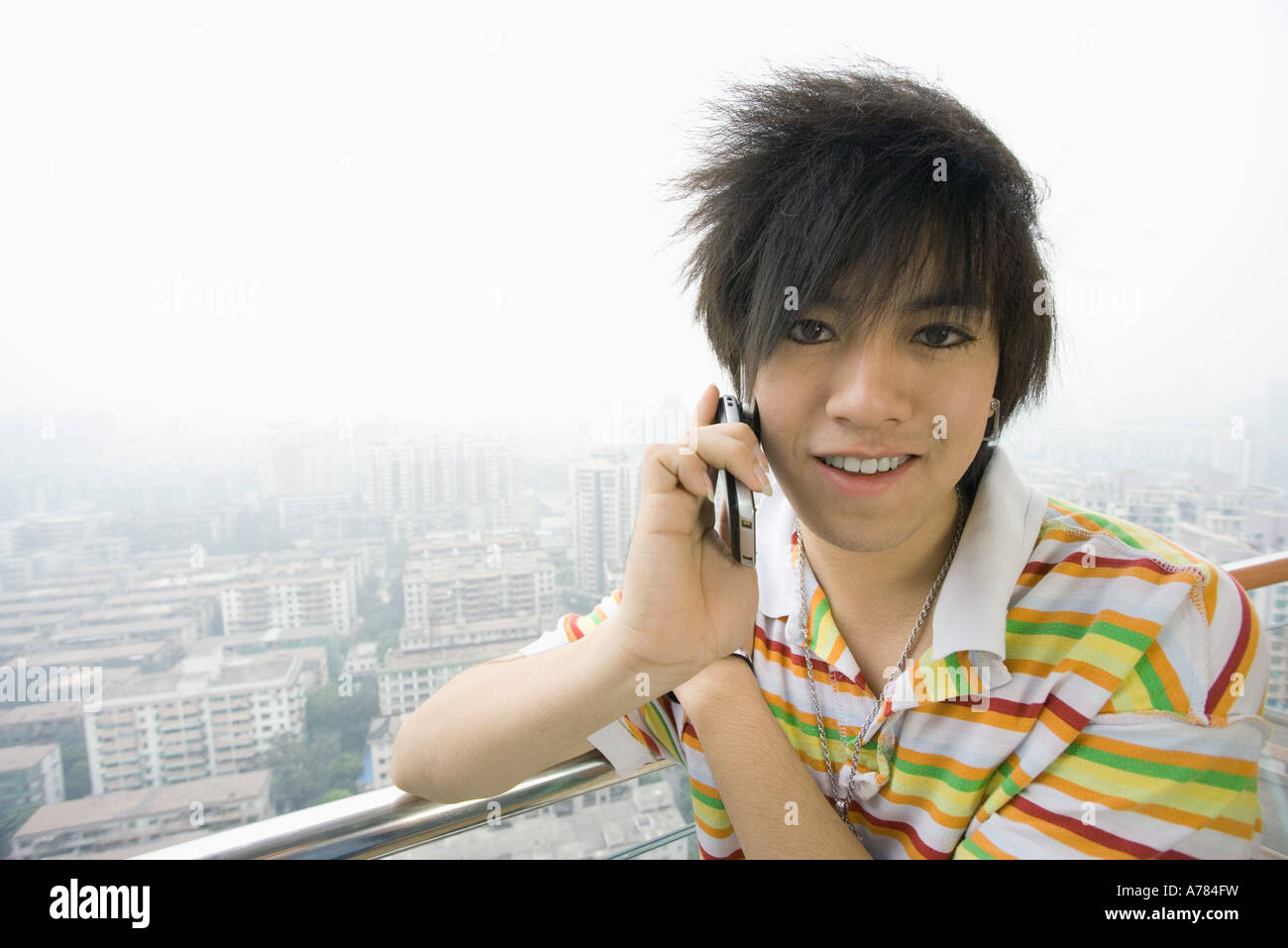 Ragazzo adolescente tramite telefono cellulare, cityscape in background Foto Stock