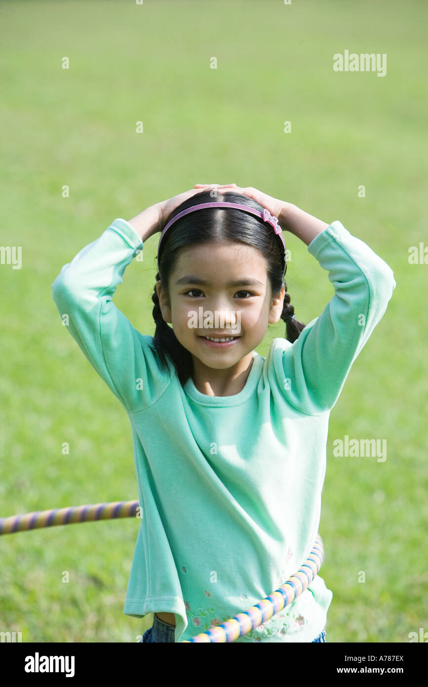 Ragazza che gioca con il cerchio di plastica, sorridente in telecamera Foto Stock
