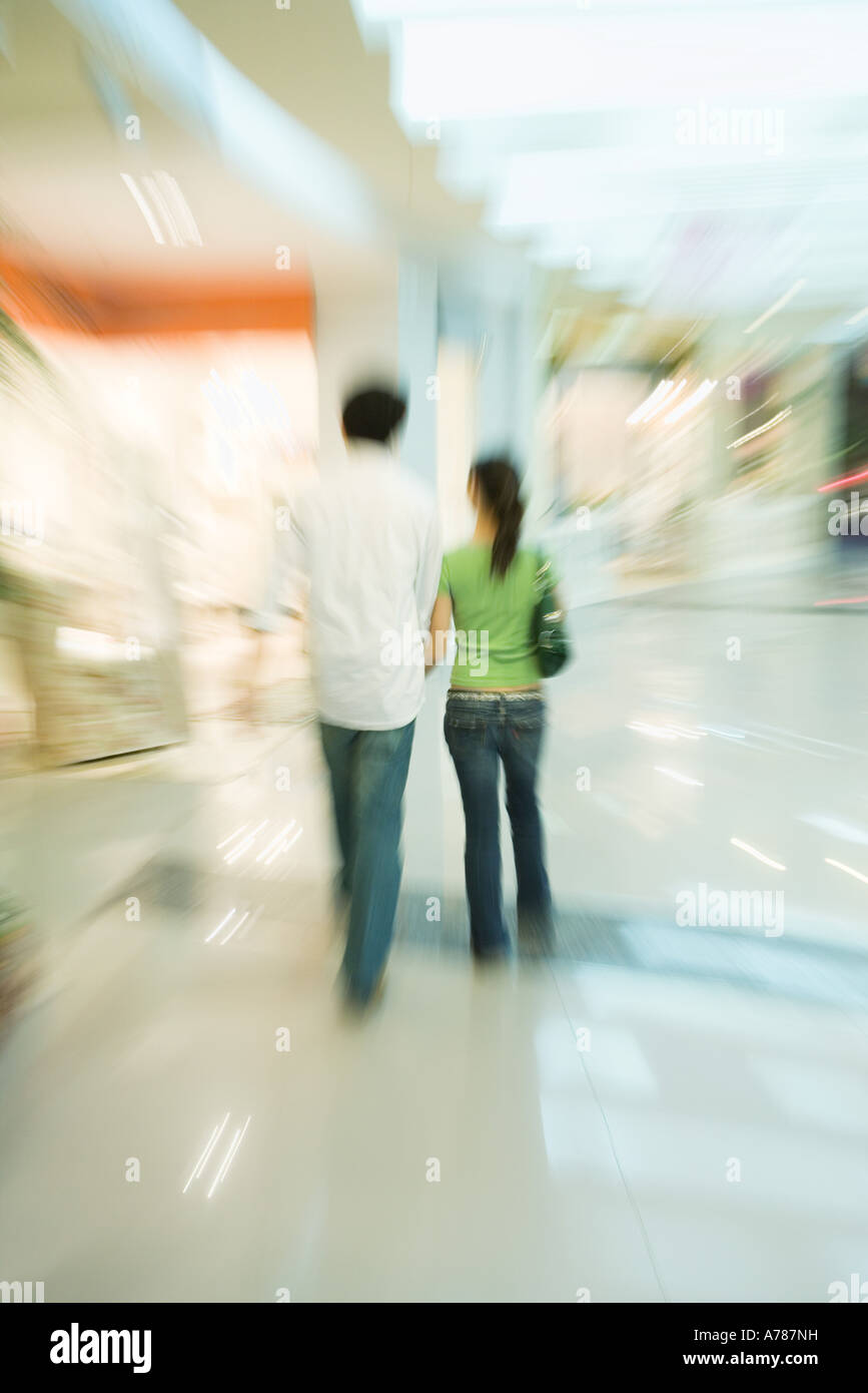 Giovane passeggiando per il centro commerciale per lo shopping, vista posteriore a piena lunghezza Foto Stock