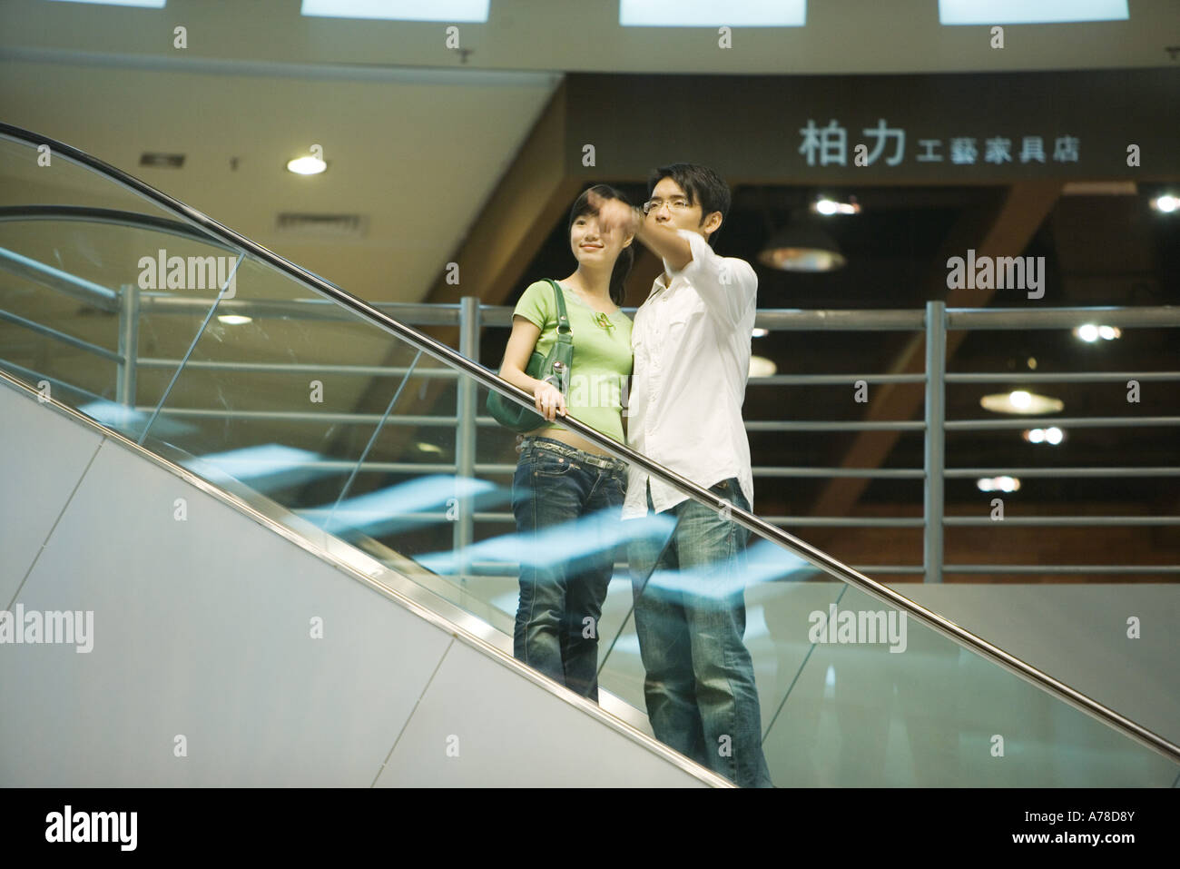 Giovane prendendo in escalator shopping mall, uomo rivolto al di fuori del telaio Foto Stock