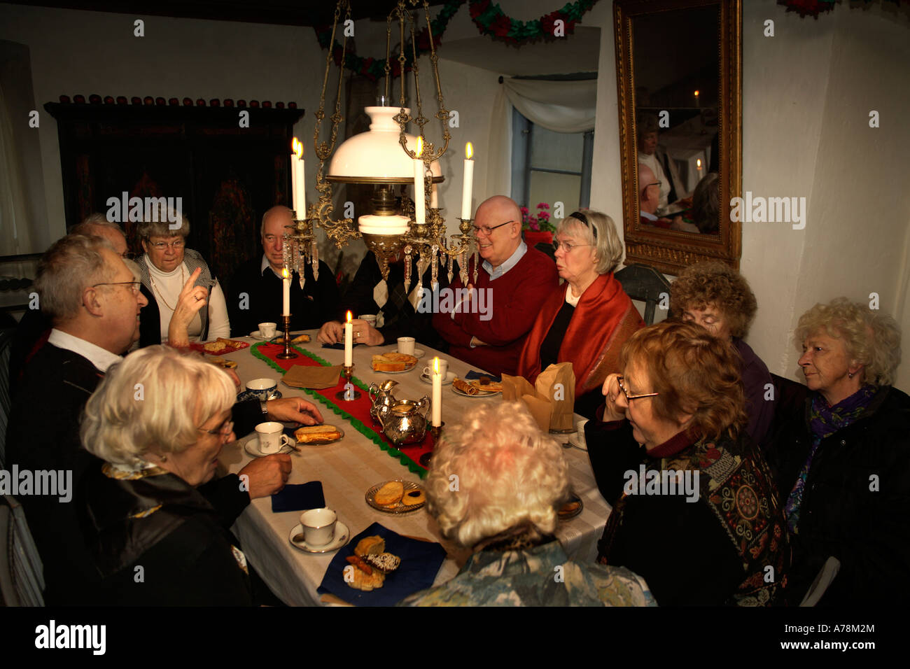 I cittadini anziani godendo solenne serata a lume di candela. Conversazione e compagnia.Le tazze di caffè e home dolci da forno. Foto Stock