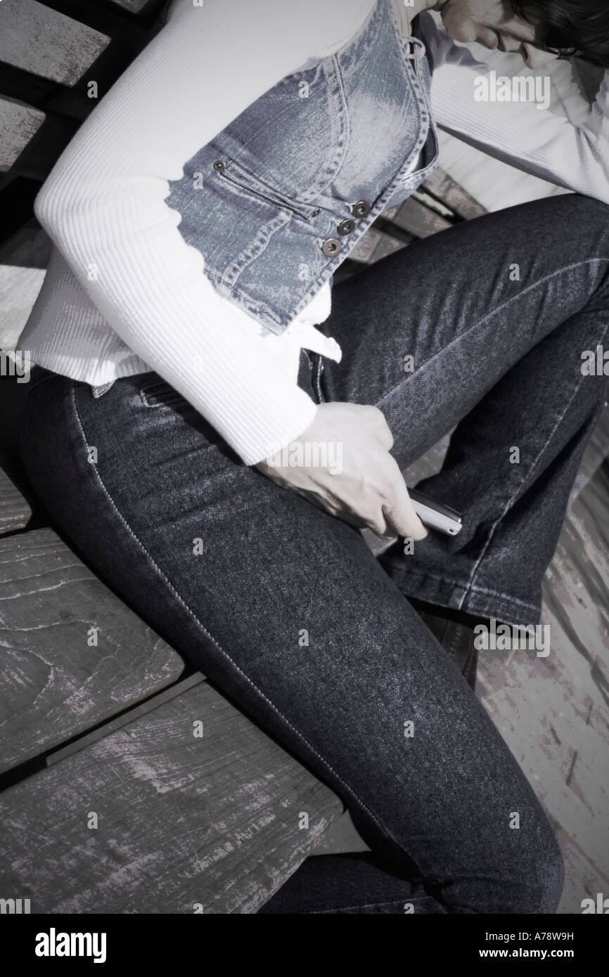 Testo freak. Immagine dissaturato e distorta, creando un effetto prospettico sulla donna mano texting, gambe e panca. Foto Stock