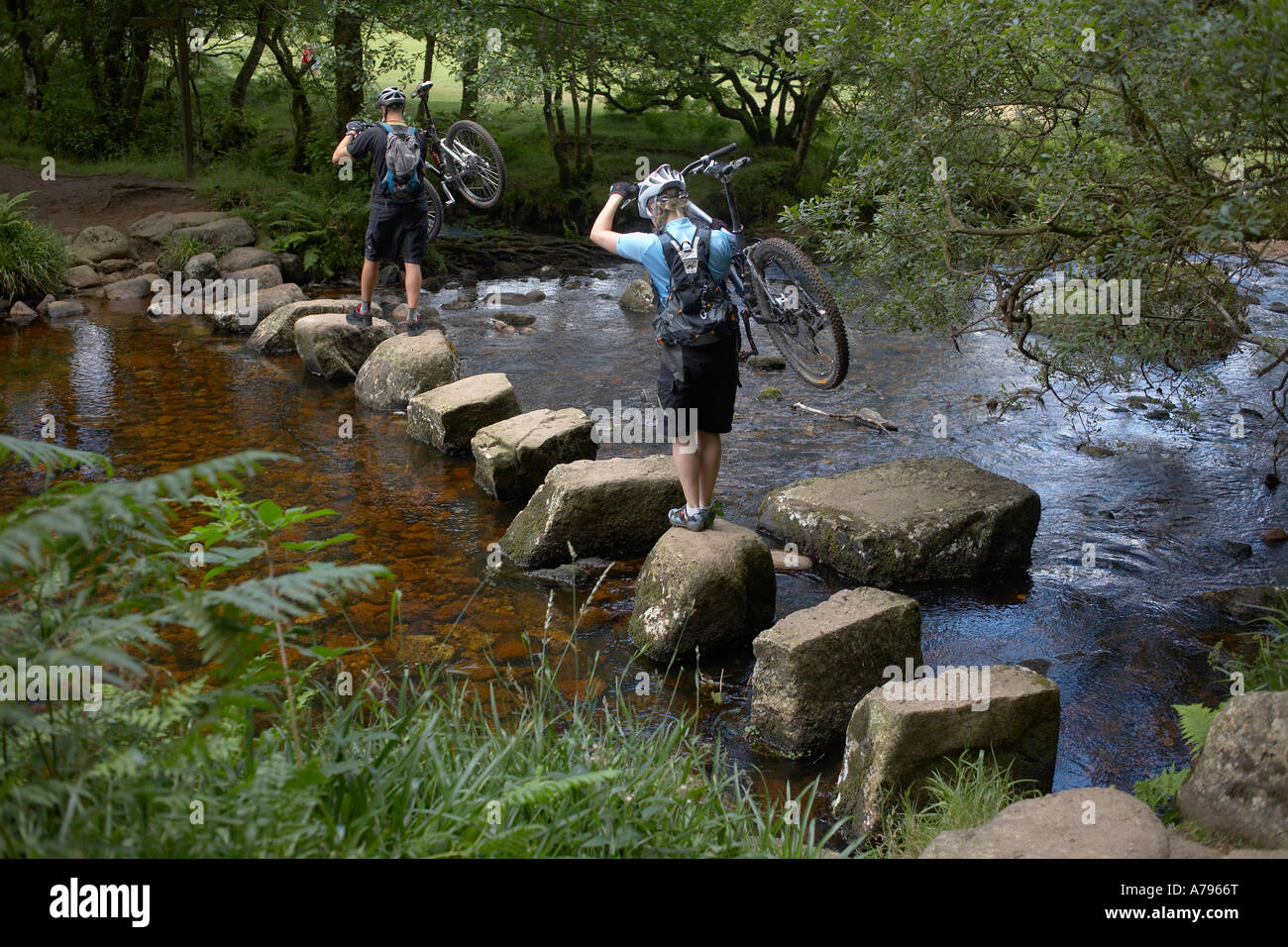 Gli amanti della mountain bike che trasportano le moto attraverso pietre miliari su Dartmoor. Foto Stock