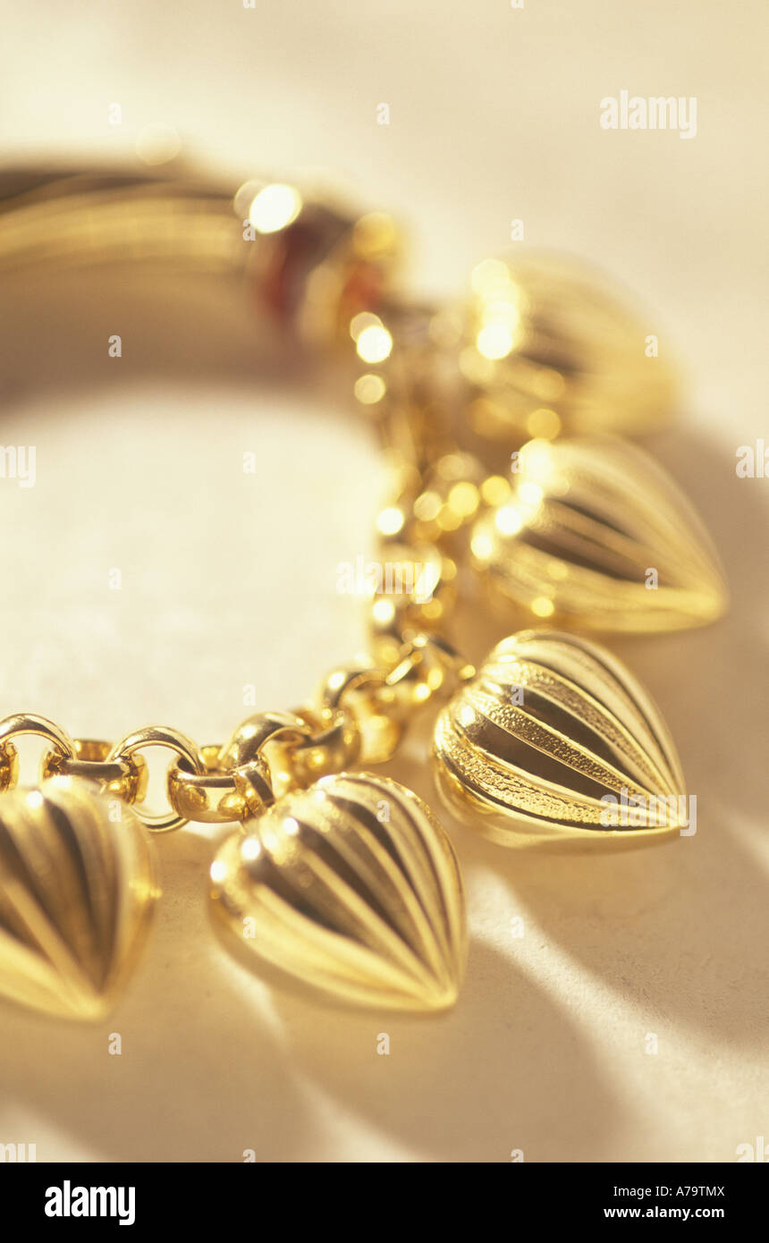 Un bracciale oro con cuore ciondoli a forma rifulge. Foto Stock