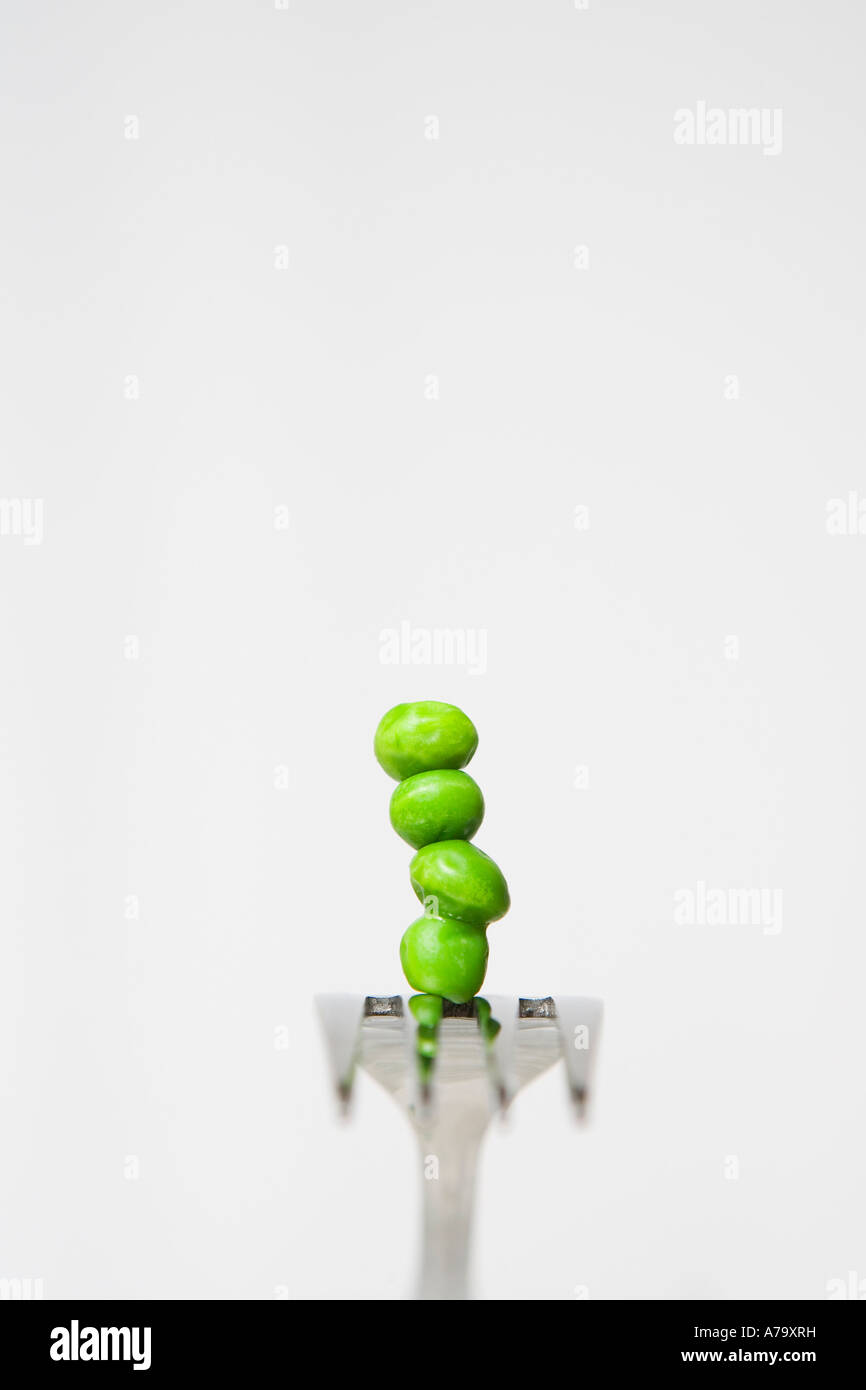 Piselli verdi bilanciato su una forcella in acciaio Foto Stock