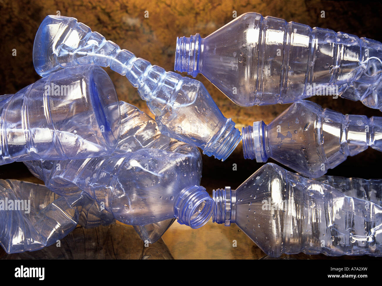 Le bottiglie di plastica deformate sono disposte artisticamente su una superficie riflettente, evidenziando i problemi relativi ai rifiuti e all'inquinamento Foto Stock