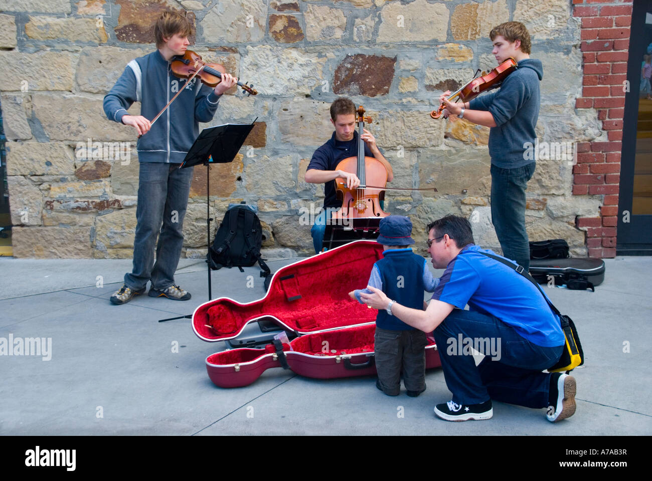 Un trio di studenti di musica classica che si recano a Salamanca Place, Hobart, Tasmania Foto Stock