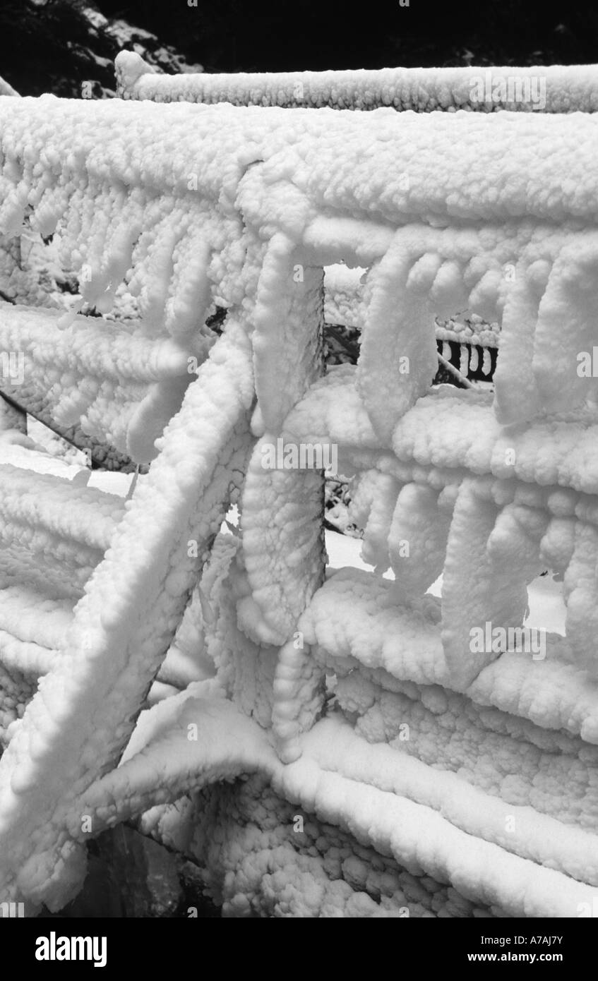 Un ponte coperto in uno spesso strato di ghiaccio dagli spruzzi di una cascata in Quebec Foto Stock