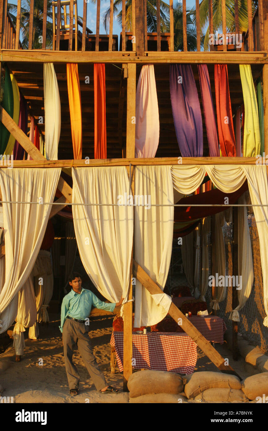 Un cameriere attende diners presso il suo ristorante sulla spiaggia di Anjuna, Goa. Foto Stock