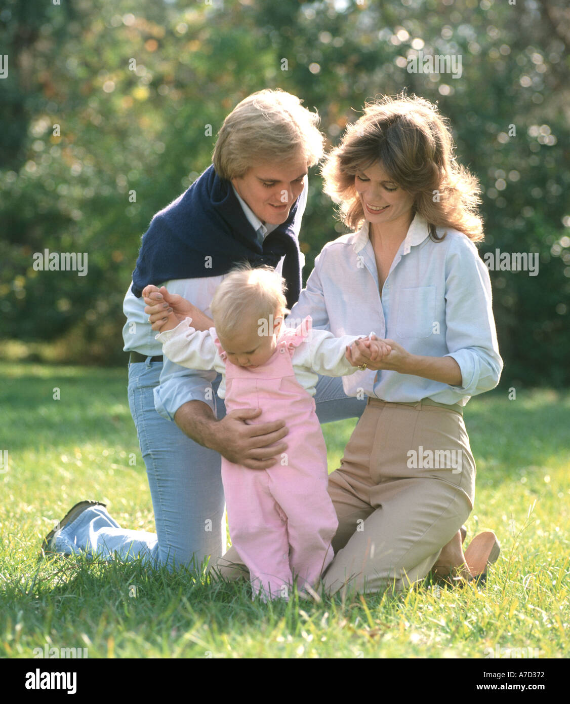 Baby girl ad imparare a camminare con i genitori in un parco Foto Stock