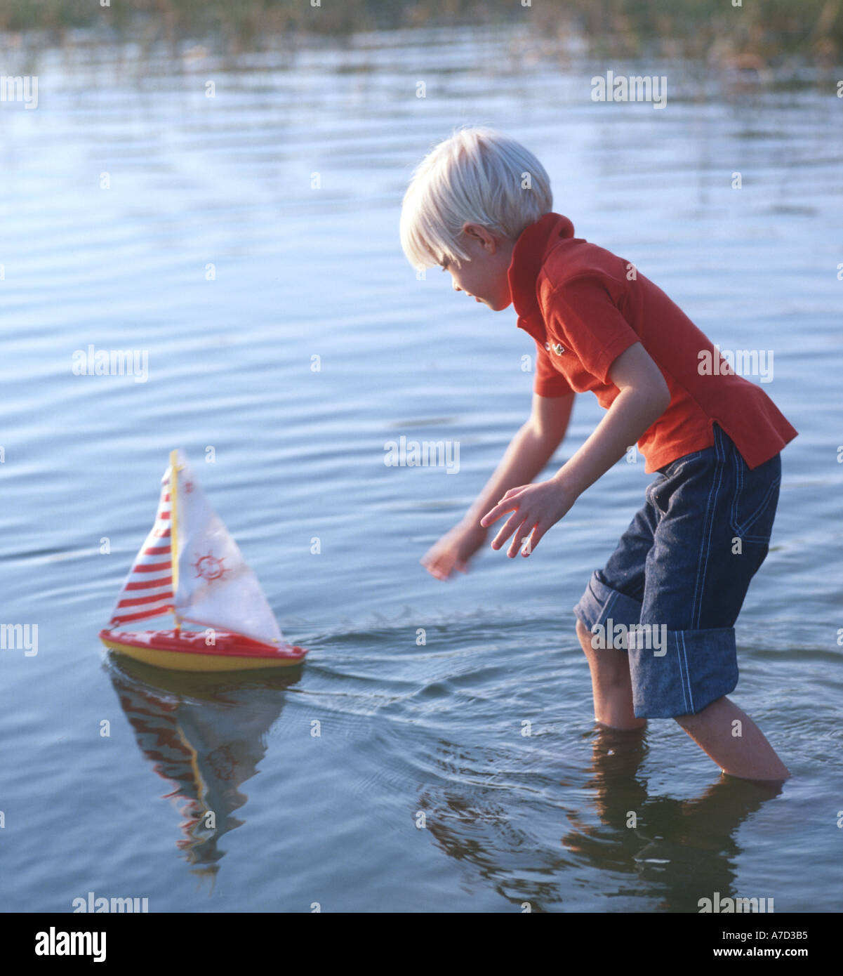 Ragazzo giocando con il giocattolo in barca a vela nel lago Foto Stock