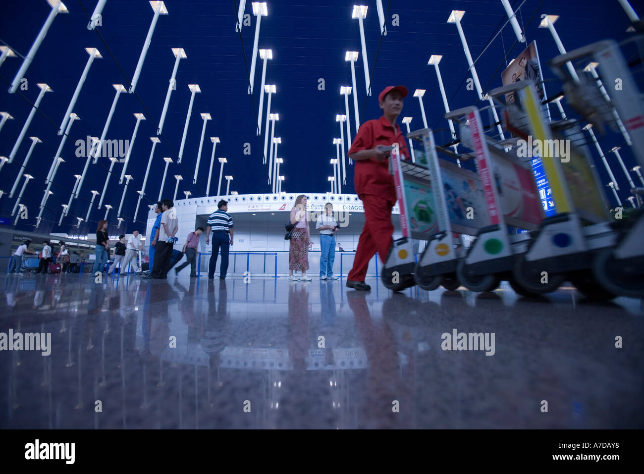 Asia Cina Shanghai i lavoratori aeroportuali ritirare il bagaglio pushcarts all'interno della aerostazione partenze dell'Aeroporto Internazionale di Pudong Foto Stock