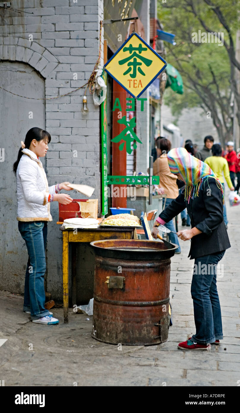 Cina XIAN giovani donne cinesi impostazione di pentola e ingredienti sul marciapiede nel quartiere musulmano di Xian per preparare il cibo Foto Stock