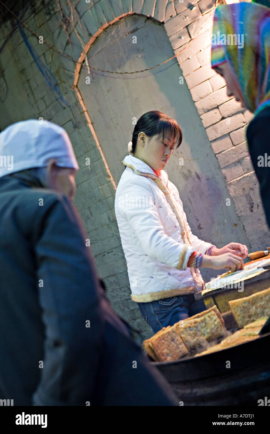 Cina XIAN donna cinese per la cottura di alimenti freschi per musulmani ai clienti al marciapiede cucina nel Quartiere Musulmano di vecchi Xi'an Foto Stock