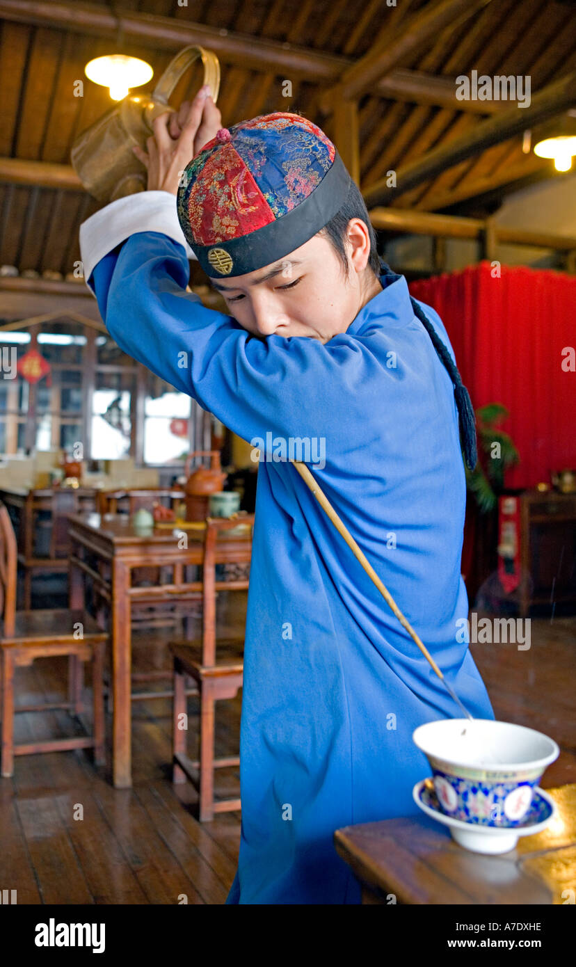 Cina HANGZHOU giovani server tè tè versa da dietro la schiena utilizzando antichi lungo beccuccio teiera Foto Stock