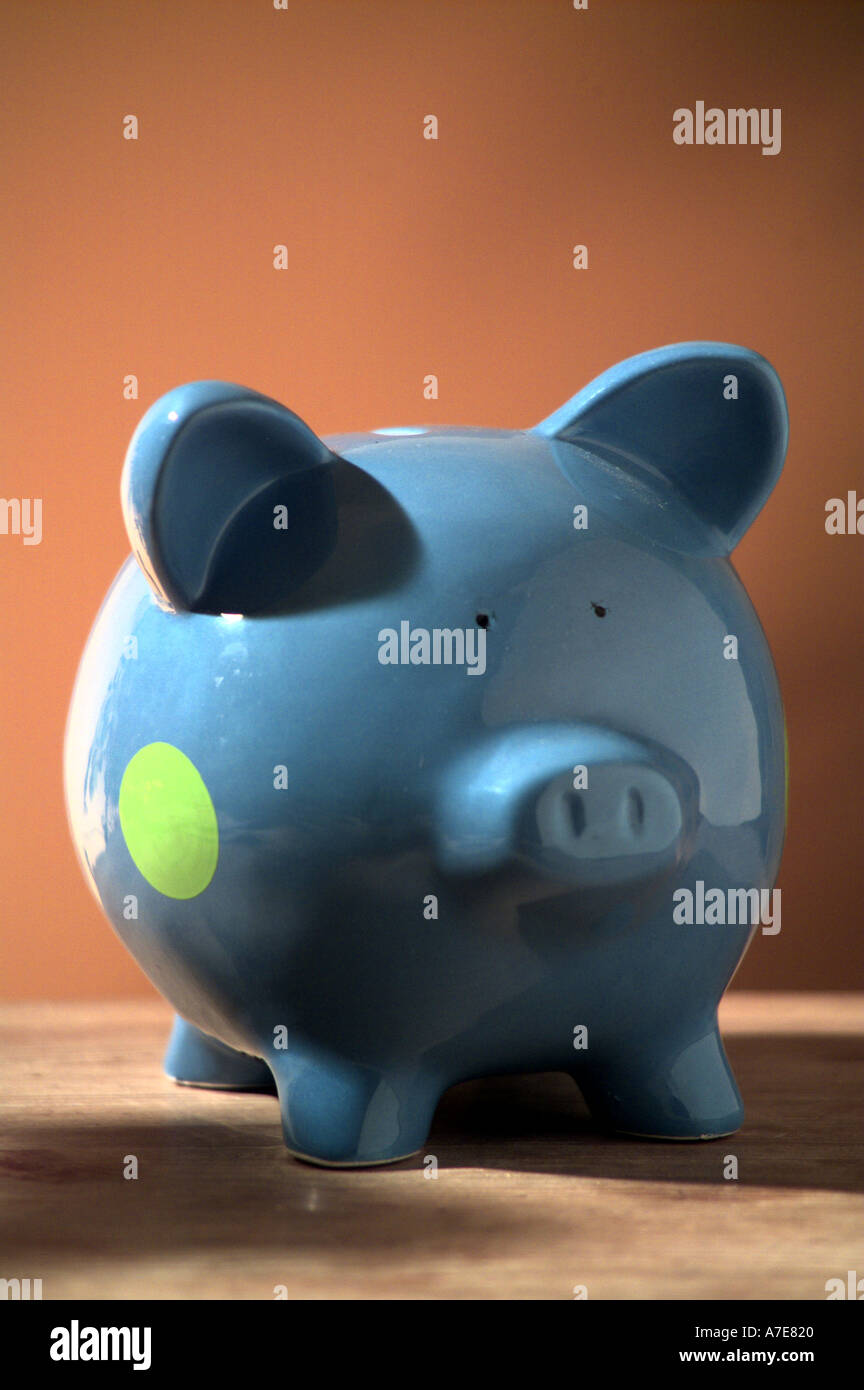 scatola di denaro blu piggy bank su sfondo marrone Foto Stock