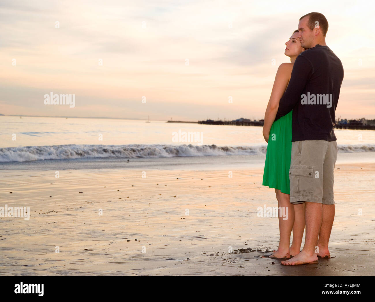 Ritratto di giovane coppia in cerca il largo in distanza al tramonto, Santa Barbara, CA Foto Stock