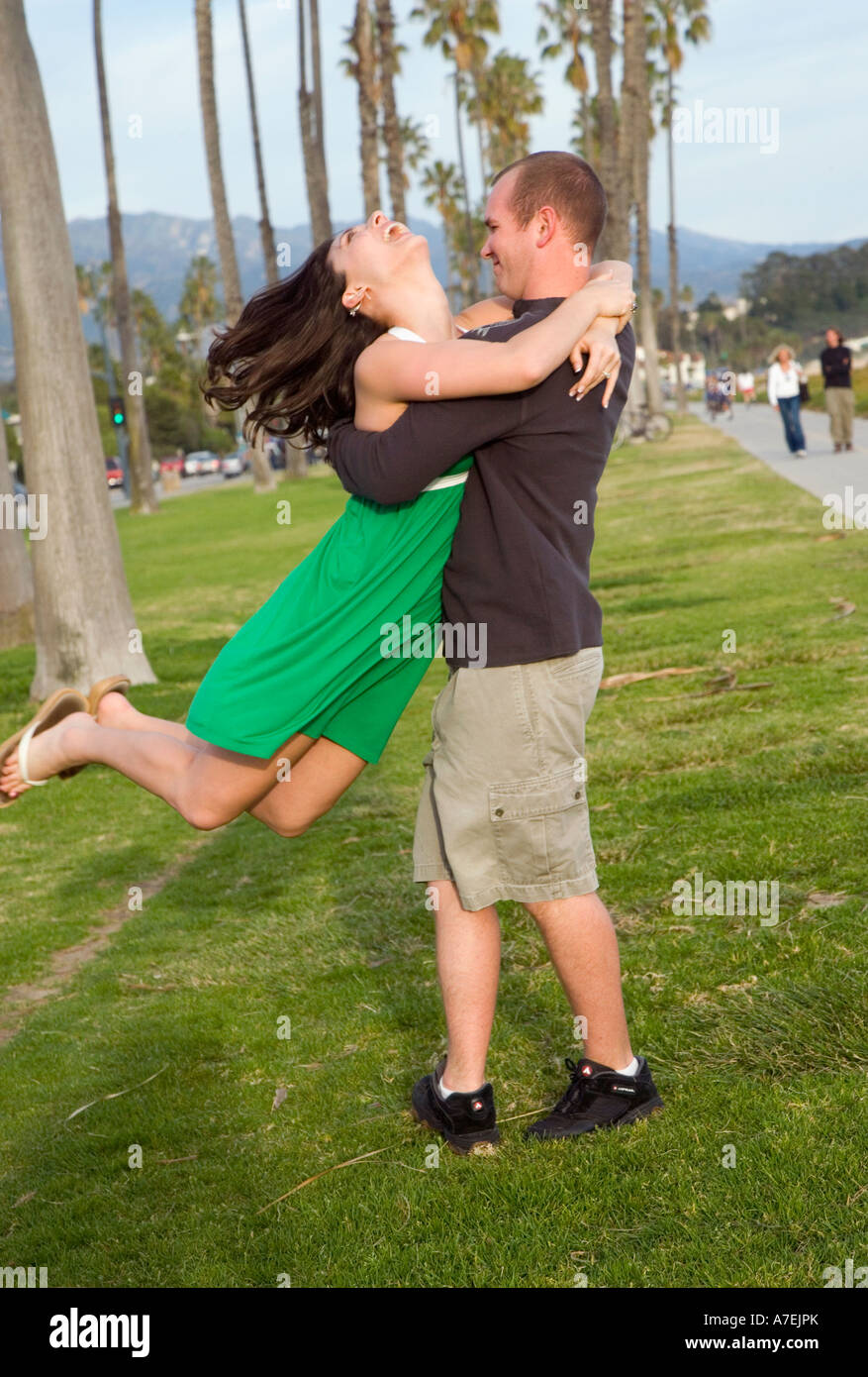 Giovane uomo ghirigori il suo fidanzato intorno nei cerchi presso la spiaggia di Santa Barbara, CA Foto Stock